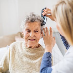 Caregiver combing hair of senior woman at home